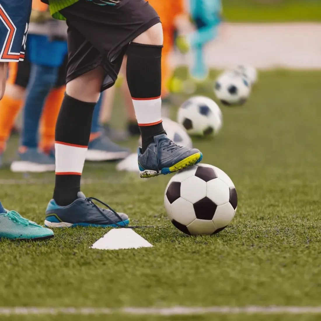 Bambini in allenamento con palloni e coni
